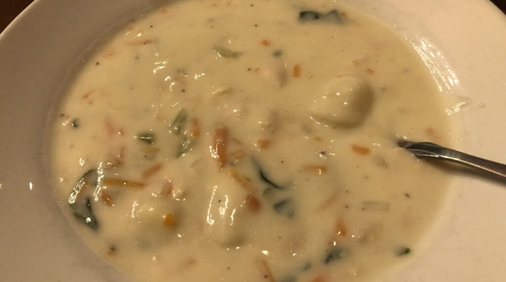 Macro close-up of creamy chicken gnocchi soup with pillowy potato gnocchi, tender shredded chicken, and baby spinach