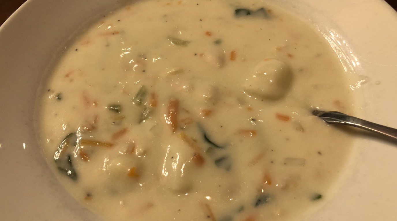 Macro close-up of creamy chicken gnocchi soup with pillowy potato gnocchi, shredded chicken, and baby spinach