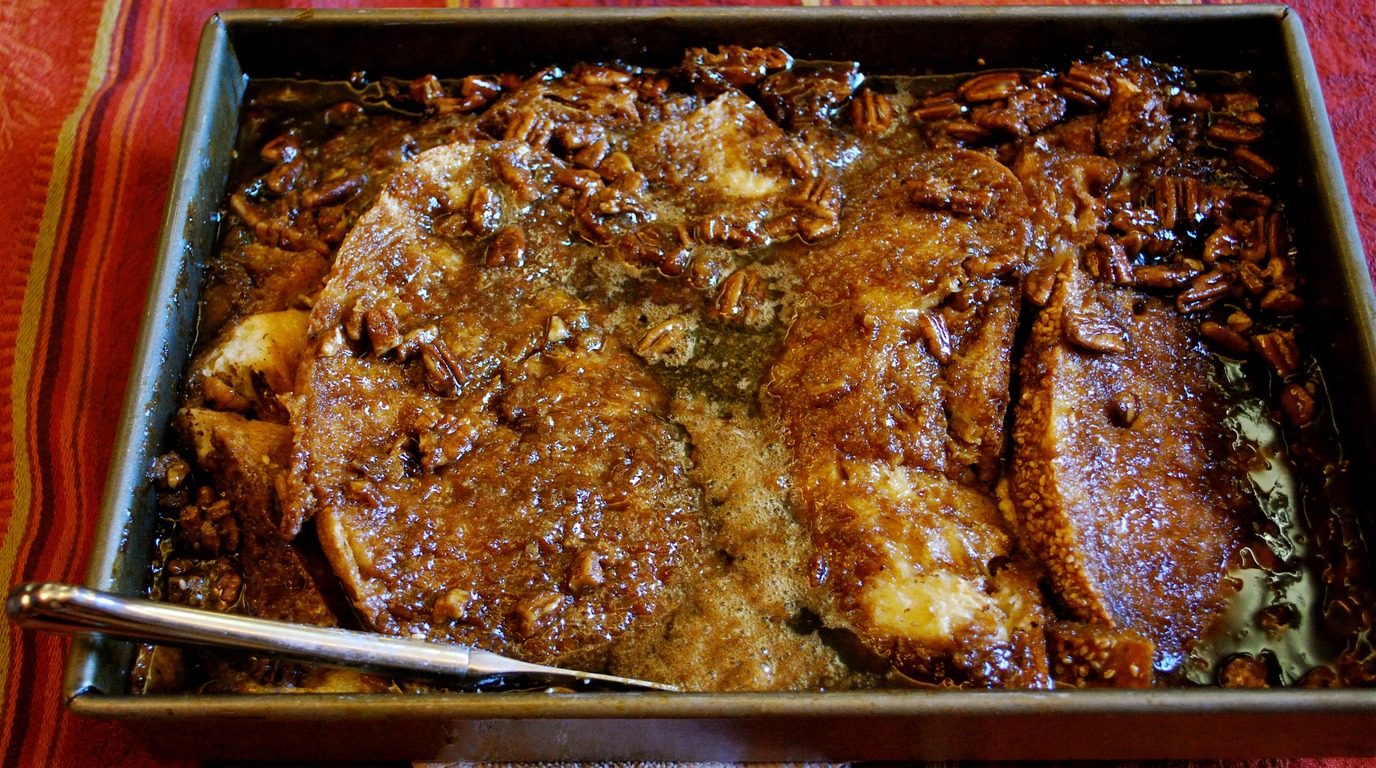 Macro close-up of golden baked brioche French toast casserole topped with bubbly cinnamon pecan streusel and maple syrup