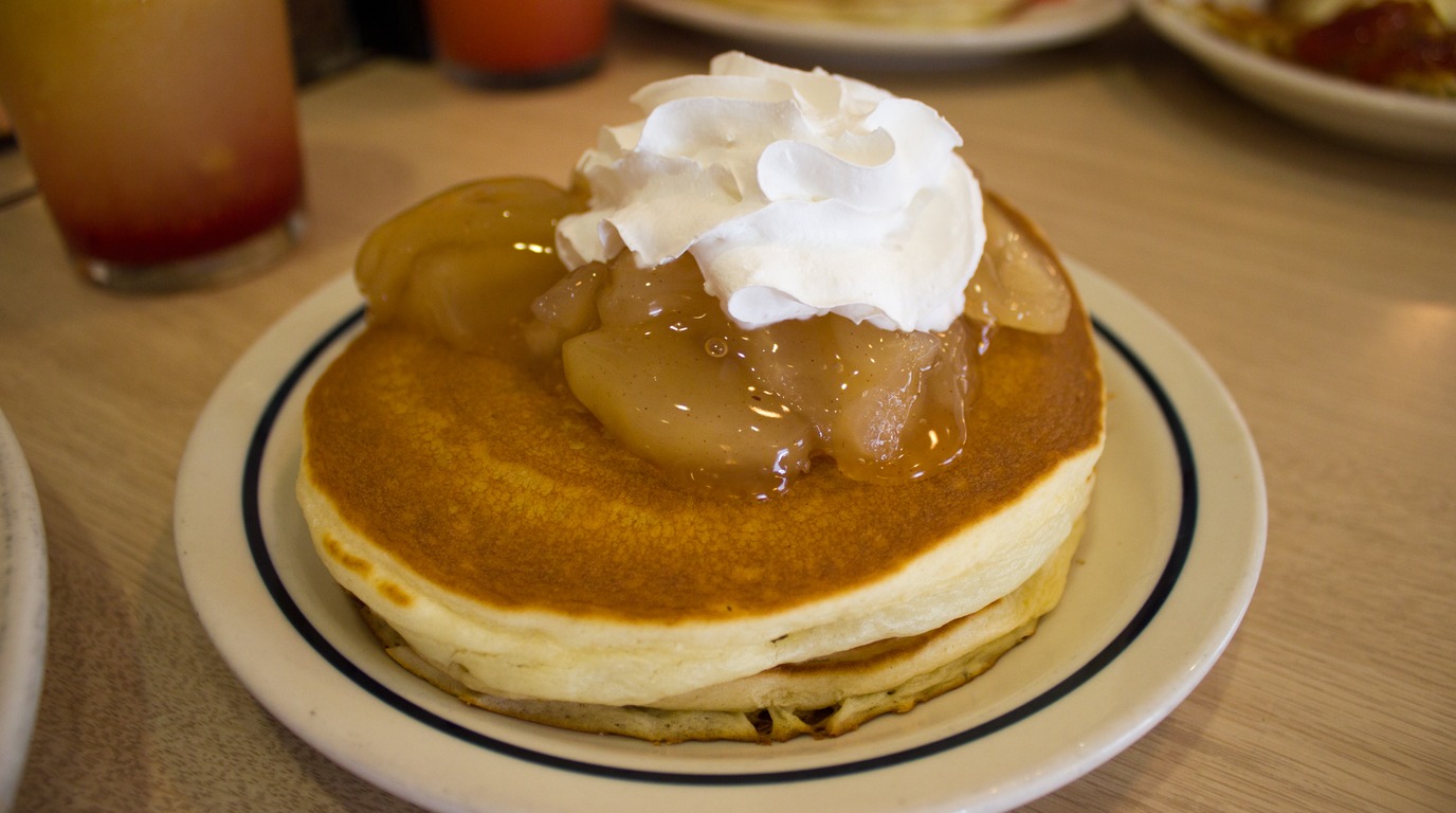 Ultra close-up macro shot of fluffy golden buttermilk pancakes with caramelized cinnamon brown sugar swirl and warm melting cream cheese glaze