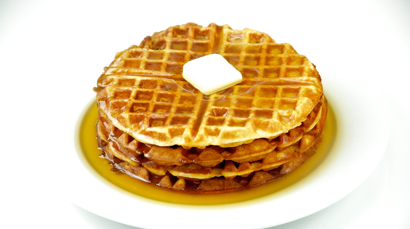 Ultra close-up macro view of golden crisp Belgian pumpkin waffle grid pockets filled with melting spiced butter and dripping pure maple syrup