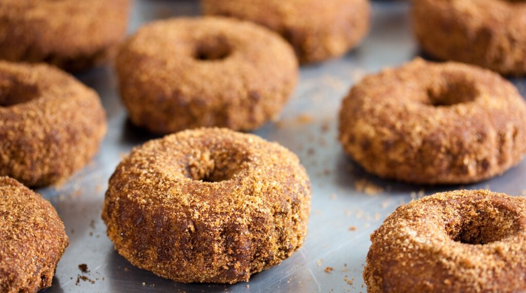 Macro close-up of golden soft baked apple cider donuts thickly dusted in sparkling cinnamon sugar
