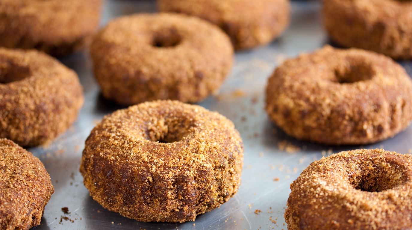 Macro close-up of golden soft baked apple cider donuts thickly dusted in sparkling cinnamon sugar