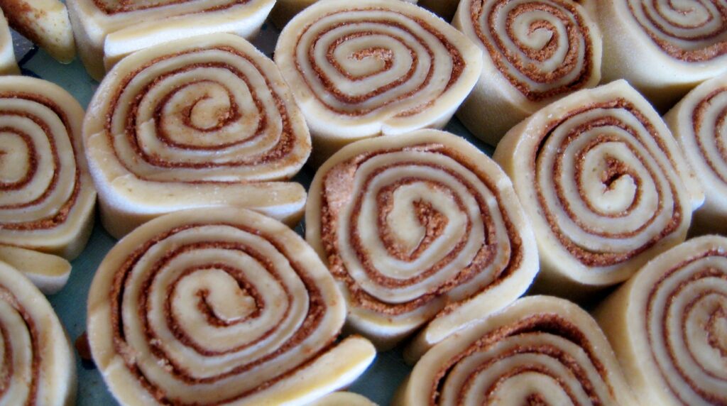 Macro close-up of warm gooey cinnamon rolls smothered in glossy cream cheese frosting